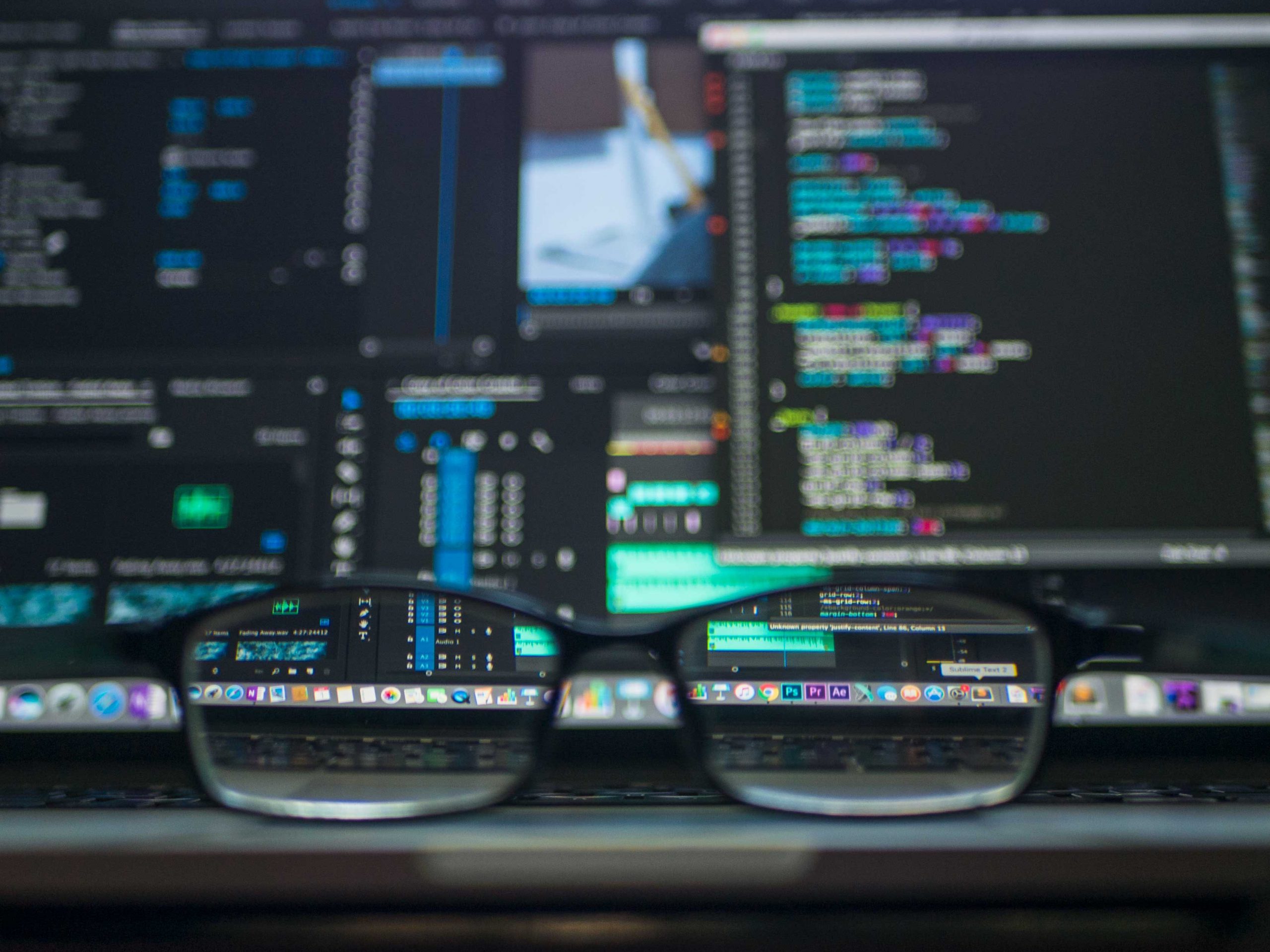 A pair of reading glasses in front of a computer screen full of web code